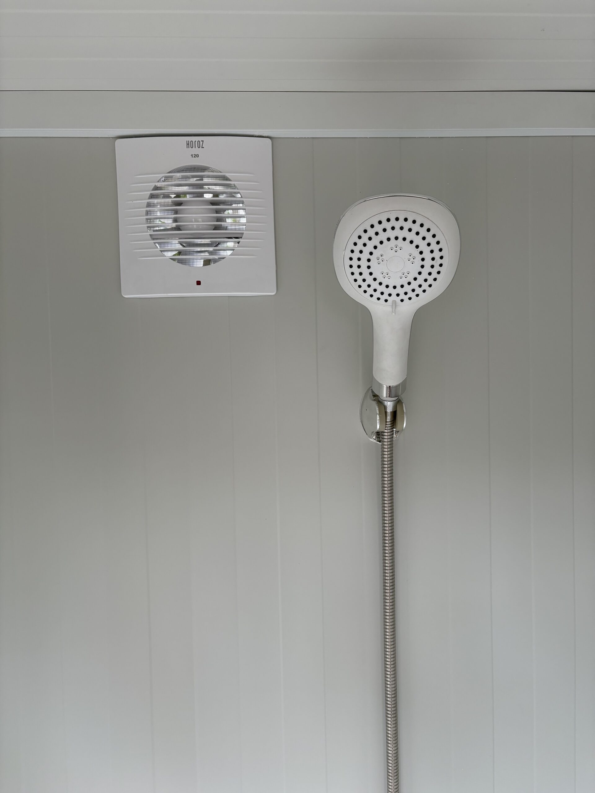 Binnenzijde van een duo mobiele douchecabine unit met douchekop en ventilatie zichtbaar
