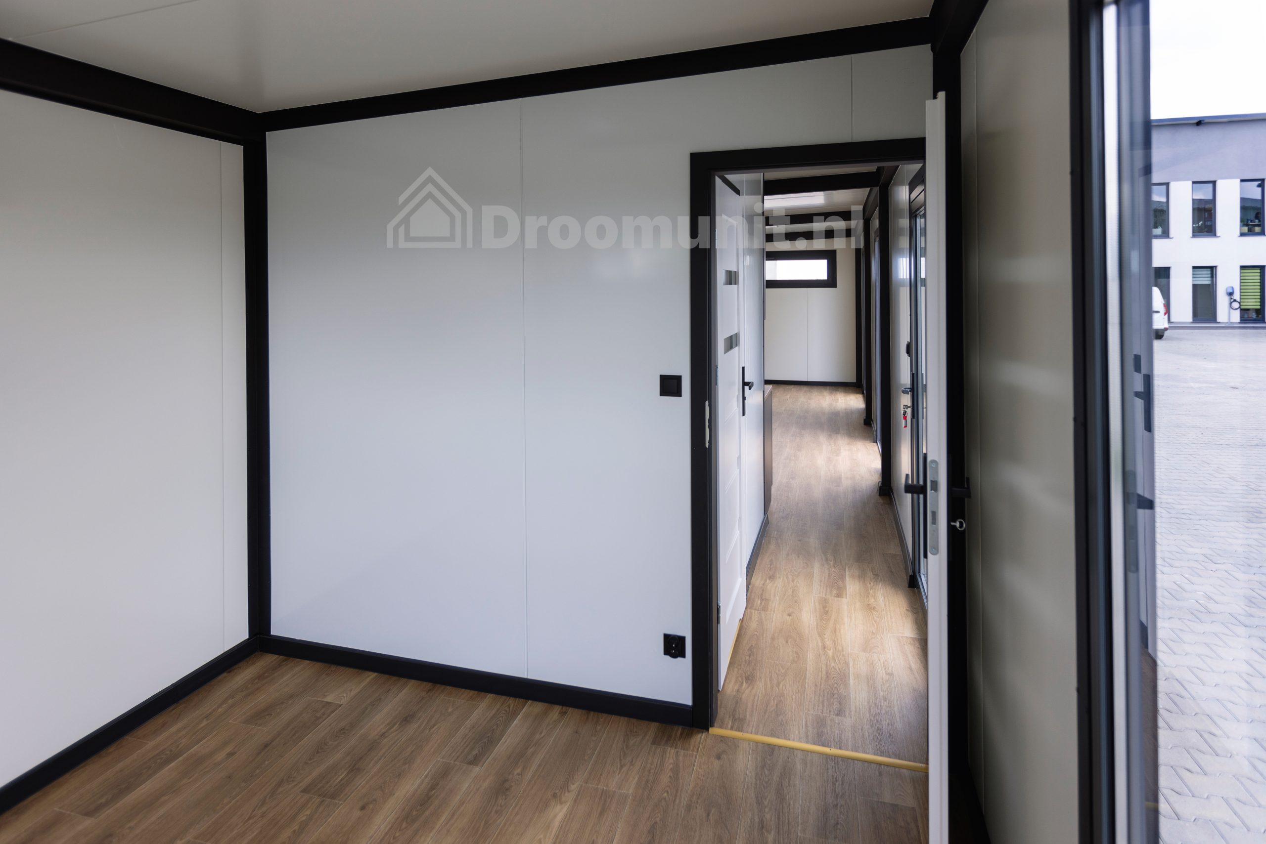 Slaapkamer met geopende deur in luxe mobiele prefab woonunit Emmy met 1 slaapkamer, afmeting 1100x300