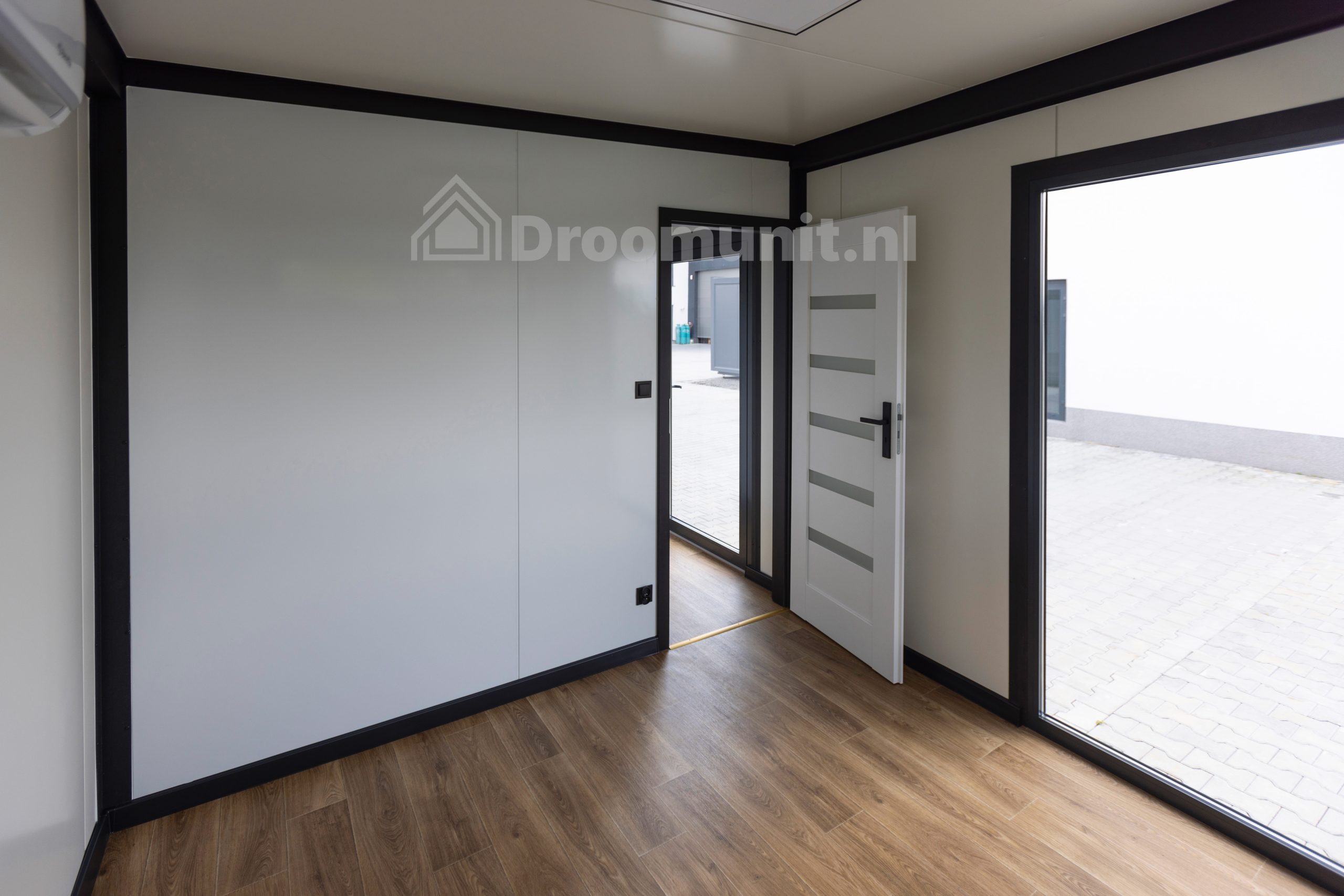 Leefruimte met kozijn en deur naar slaapkamer in luxe mobiele prefab woonunit Emmy met 1 slaapkamer, afmeting 1300x300