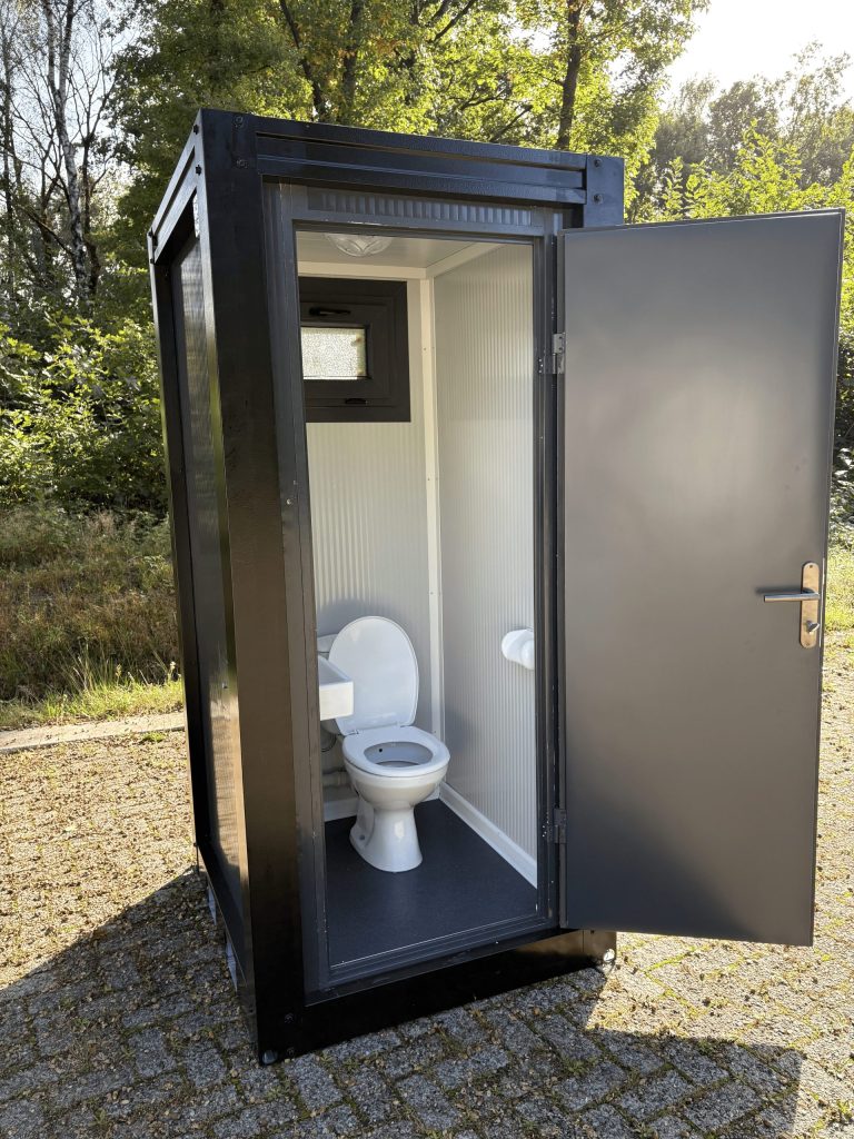 Buitenaanzicht van een mobiele toilet unit met links geopende deur