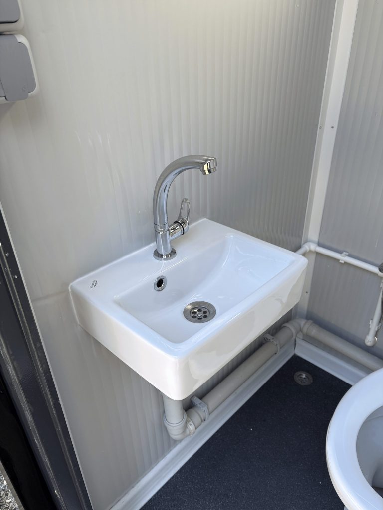 Close-up van wastafel met kraan in een mobiele toilet unit